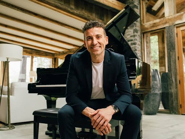 Corporate keynote speaker and musician Cameron Atlas sitting by a grand piano.