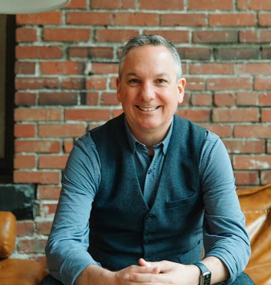 Dan Chuparkoff, global keynote speaker and artificial intelligence educator, in front of a brick wall.