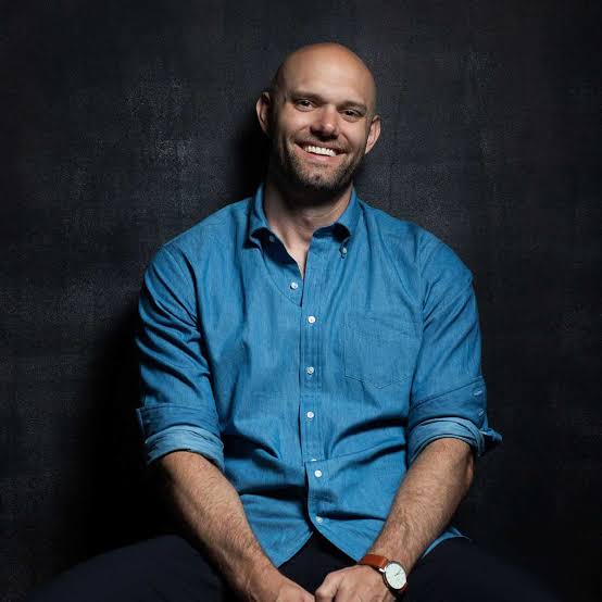 James Clear, author and keynote speaker, posing against a dark background.