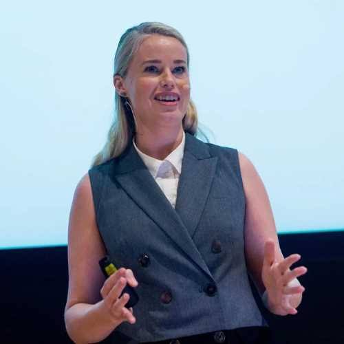 Dr. Jessica Barker speaking on stage at a corporate event or conference.