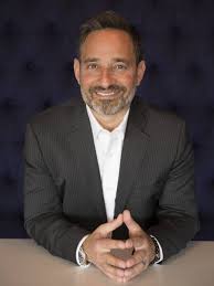 Josh Linkner, keynote speaker, entrepreneur, and bestselling author, smiling in a suit.