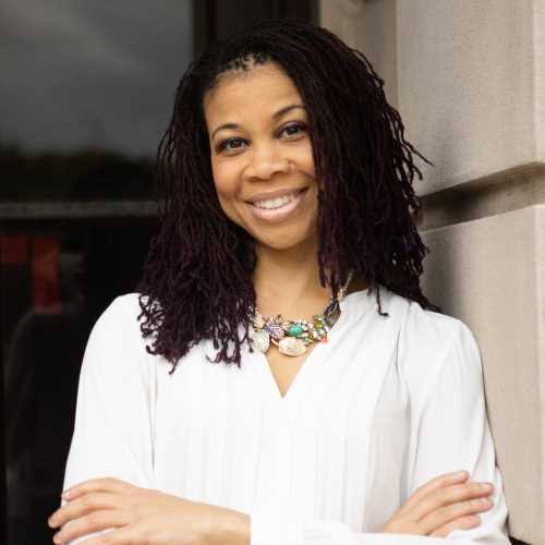 Portrait of keynote speaker and HR executive Kim Blue smiling outdoors.