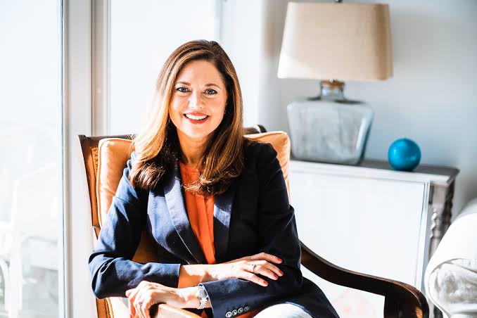 Personal finance expert and keynote speaker Laura D. Adams seated in an armchair.