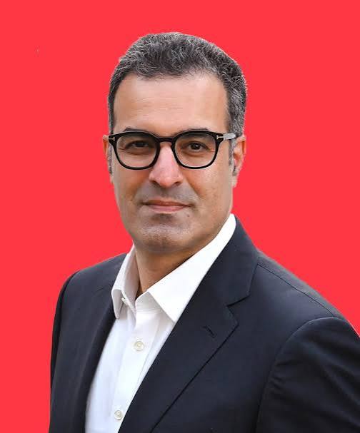 Portrait of keynote speaker and customer experience expert Lior Arussy against a red background.