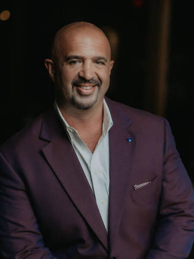Keynote speaker and leadership advisor René Rodriguez wearing a purple blazer.