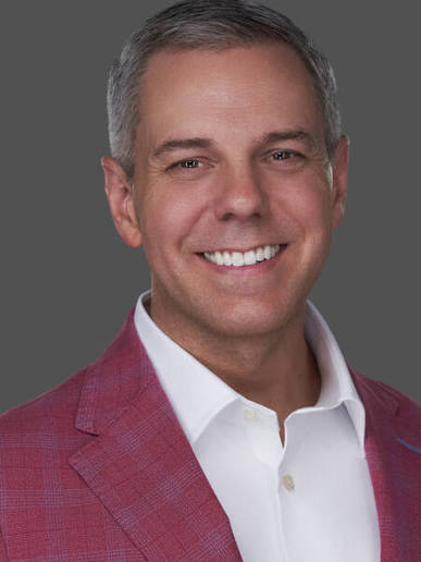 Keynote speaker and CX expert Ryan Minton smiling in a red blazer.
