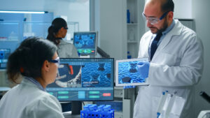 Medical researchers collaborating in a laboratory analyzing healthcare AI data on screens and a tablet.